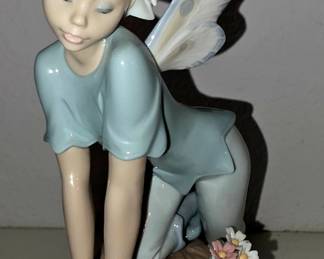This is Lladró “Butterfly Wings Fairy” #6875 — glossy porcelain fairy on a rock with flowers, sculpted by Alfredo Llorens. The official Lladró listing shows it as SKU 01006875, launched in 2003,