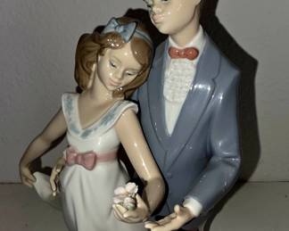 Lladró porcelain figurine, likely model #5555 “First Kiss” / “Bashful Bather” — boy in blue suit with girl in white dress holding flowers.