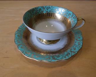 This is an Eberthal Bavaria porcelain teacup and saucer set featuring a mint green and gold filigree design.