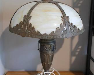 This antique Miller Company table lamp features caramel slag glass panels and a decorative metal base.Manufacturer: Edward Miller & Co.Era: Victorian or Arts and Crafts (circa 1910s-1920s)Design: Curved 6-panel slag glass dome with metal overlay.