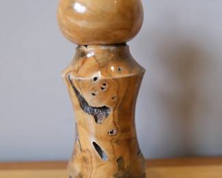 Rustic pepper mill. The Maker: Brett Knutson is a recognized woodturning artisan who creates high-quality, handcrafted custom salt and pepper mills. He is particularly well known as a long-time craft vendor at the historic Pike Place Market in Seattle, Washington.The Material: His signature work often utilizes salvaged, domestic, and exotic logs—such as western burls, figured maple, and rescued timber—which he seasons in drying kilns before hand-turning them on a lathe. The deep natural voids, dark bark inclusions, and swirling grains seen in your photo are intentional design choices to highlight the organic character of the wood.