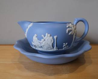 This is a vintage Wedgwood Jasperware creamer in blue with white classical relief figures, featuring a matching saucer.