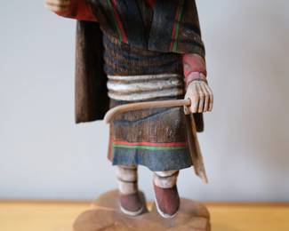 Earl Inptewa (Talayu) is a recognized contemporary Hopi carver who specializes in creating traditional Katsin Tihu (Kachina dolls).He is known for his highly detailed, traditional carving work using cottonwood root and mineral pigments. His figures often emphasize historic accuracy and the distinct spiritual traits of the Katsinam. This carved wooden figure is a Hopi Soyok Wuhti Kachina doll, often referred to as a "Monster Woman" or Ogre Woman.Cultural Significance: In Hopi tradition, this spirit appears during the Powamu ceremony to threaten children for misbehavior. Note condition issues of missing knife and broken cane.