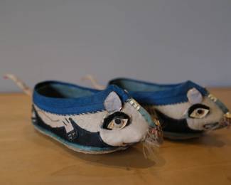 These are traditional Chinese hand-made child's shoes, often referred to as tiger-head or lion shoes, featuring blue and white fabric with detailed embroidered eyes.