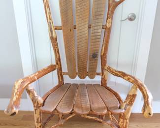 This chair is a signature creation by Ken Wheeler, a highly regarded "green" artist and woodworker based out of Saluda, North Carolina. The Materials: Ken Wheeler specializes in crafting one-of-a-kind rustic furniture using locally sourced branches (such as native rhododendron and mountain laurel) alongside highly textured reclaimed farmhouse wood. Design Philosophy: He intentionally highlights the natural history of the wood, embracing character elements like unique patinas, old nail holes, and natural tree limb forks.