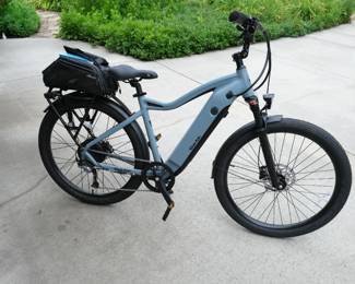 This is a Ride1UP 700 Series electric commuter bike in a blue-gray color, equipped with a rear rack and a pannier bag.