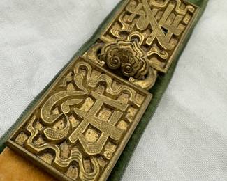 A 19th century Chinese Qing Dynasty gilt-bronze belt buckle with ruyi shape hook, one half of the buckle with a Chinese character xiào translated as "filial piety" and the other half with "zhōng" translated as loyalty, faithfulness, or devotion. Measurements approximately 3-⅝” long. Has handwritten paper card attached that reads “Chinese belt buckle relic of the Boxer Uprising in Peking China in 1900”
