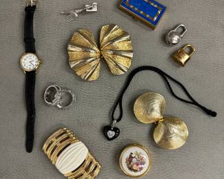 A Timex Indiglo wristwatch with black band; two different gold-tone seashell form belt buckles; a silver-tone knife and fork shape tie pin, a Limoges porcelain pillbox handpainted with classic courting couple scene; a gold-tone and blue enamel rectangular pill box, and more!