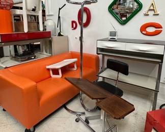 A bright orange couch for that retro vibe; a chrome standing valet or coat rack, a Raymond Loewy DF2000 white two-drawer console with stand, a circa 1965 Kevi office chair, designed by Danish architect and designer Jørgen Rasmussen; stamped underneath with Made in Denmark by KEVI of Copenhagen; and a late 20th Century Houghton Mifflin reading or laptop table with adjustable angle and heights, on casters, unmarked