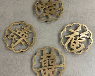 A vintage set of brass trivets or coasters in the form of Chinese characters for good luck, within cloud- or flower-shaped borders
