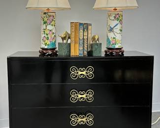 Another view of one of the stunning pair of mid-century Harvey Probber black lacquered chests from the Merchandise Mart in Chicago, shown with pair of Chinese Jingdezhen famille rose enamel porcelain vases with colorful bird and floral motif, converted to lamps and resting on carved wood stands; vintage books, and modernist brass and marble bull book ends 