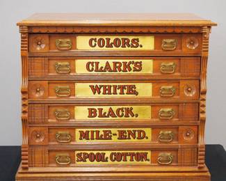 A turn of the century Clark's Spool Cabinet. Oak construction features six labeled dovetailed drawers with brass handles and painted red and gold labels. Older refinish with some wear, replaced drawer labels (includes the original very worn labels in a drawer). 25 x 18 1/2 x 21 3/4" high overall. ESTIMATE $400-600