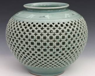 A Korean Goryeo-style reticulated Celadon porcelain vase. Rounded form double wall porcelain vase with reticulated basketweave design about the body and flying crane and cloud pattern above the shoulder with crackle glaze overall. Marked at the underside. Minor wear. 9 3/8" diameter, 8" high. ESTIMATE $600-800