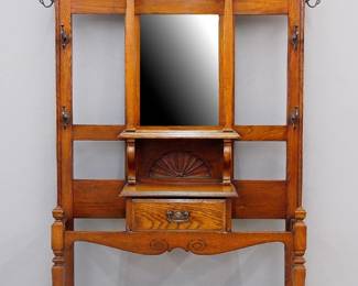 A turn of the century English hall tree. Oak construction features an arched crown with carved shell over a beveled glass mirror flanked by columns and carved foliate panels above a dovetailed glove drawer flanked by umbrella holders with metal drip pans, original iron coat hooks. Original finish with minor wear. 45 x 14 x 83" high overall. ESTIMATE $400-600