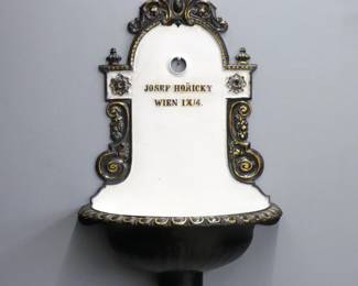 A late 19th century Lavabo by "Josef Horicky, Wein, 1X/4". Cast Iron construction with shaped back and foliate scrolls above a half bowl with scalloped edge. Re-painted Black and White finish with Gold detail, minor wear. 32" high. ESTIMATE $200-300