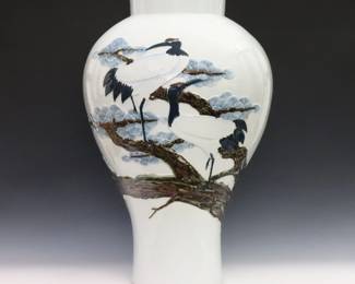 A Korean Blue and White porcelain vase. Inverted baluster form decorated with a high relief design of a pair of Cranes perched in pine boughs amidst clouds. Marked at the underside. Minor wear. 25" high. ESTIMATE $2,000-4,000