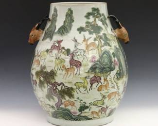 A Chinese porcelain "Hundred Deer" vase. Baluster form vase with two molded Stag form handles at either side, having a white ground and polychrome enamel decoration depicting a multitude of deer within a tree and rock filled landscape. Bearing a Qianlong red mark at the underside (China, Qing dynasty, 19th century). Some light wear overall. 14" diameter x 17" high. ESTIMATE $1,000-2,000