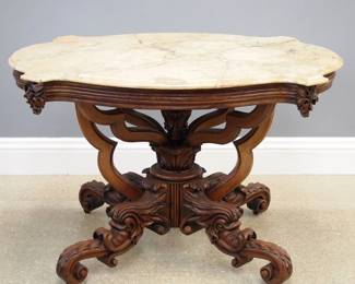 A late 19th century American Victorian Period Renaissance Revival center table. Walnut construction with a molded apron and shaped Caramel marble top over four scrolled legs and a central turned column and scrolled outer supports. Older finish with some wear, some staining and discoloration and filled repair to the marble. 41 1/2 x 35 1/2 x 29 1/2" high overall. ESTIMATE $400-600