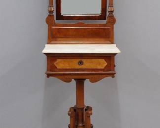 A late 19th century American Victorian Eastlake gentleman's shaving stand. Walnut construction with carved detail features a tilting mirror over a molded marble top, single drawer and a base with four shaped legs on a turned central support. Older refinishing with wear, minor repairs, some staining to the marble. 19 1/2 x 15 1/2 x 74" high overall. ESTIMATE $400-600