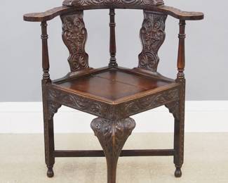 A late 19th century English Victorian corner chair. Oak construction with Jacobean style carved design features a curved back with shaped crest above shaped splats flanked by turned supports over a paneled seat and cabriole front leg. Old dark finish with wear, shrinkage crack in seat. 18 1/2 x 18 1/2 x 32 1/2" high overall. ESTIMATE $300-400