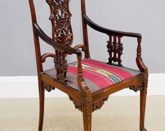 A turn of the century Chinese armchair. Rosewood construction with carved detail features an open back with reticulated center splat, shaped arms with carved supports, upholstered seat and slender cabriole legs. Older finish with some wear. 20 1/2 x 19 x 39 1/2" high overall. ESTIMATE $200-300