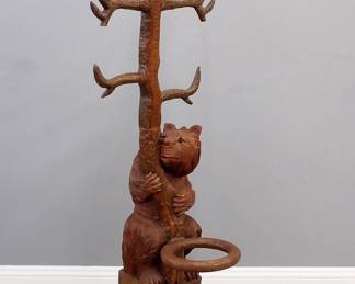 A late 20th century Black Forest style figural hall tree. Carved hardwood construction depicts a mother bear with her cub in the branches of a tree which form the coat hooks over a lower cane rack. Some finish wear, shrinkage cracks and filled repairs. 25 x 26 x 79" high overall. ESTIMATE $800-1,200