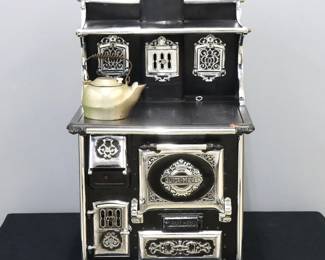 A turn of the century Child's "Quick Meal" wood burning kitchen stove. Cast Iron and steel construction features an upper warming shelf with fold down shelves and incorporated stovepipe, over a flat cook top with six burners and a lower oven with additional smaller doors. Fully restored in working order with minor wear, short crack in cooktop frame. 17 x 16 1/2 x 26 1/2" high overall. ESTIMATE $600-800