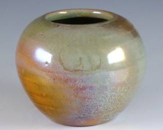 An early 20th century Pewabic Pottery vase. Round form with iridescent glaze in shades of Pale Green, Gold and Pale Purple. Retains the original medallion "Pewabic Detroit" paper label c. 1915-1930. Crazing, very slight surface wear. 3 1/2" diameter x 2 3/4" high overall. ESTIMATE $300-500
