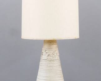 A Mid Century Modern Stoneware table lamp by Jean Hazen, Ann Arbor Potters Guild, Michigan. Tapered form with ribbed texture and mottled Beige and Tan matte glaze with a period shade. Incised "JH" monogram by cord. Minor wear. Vase is 26" high, 44" high overall with shade. ESTIMATE $200-300