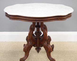 A late 19th century American Victorian Period Renaissance Revival parlor table. Walnut construction with a molded apron and Oval White marble top over four scrolled legs and a central turned column with Burl Walnut detail. Older finish with some wear, some staining and discoloration to the marble. 30 1/2 x 22 x 27 1/2" high overall. ESTIMATE $200-400
