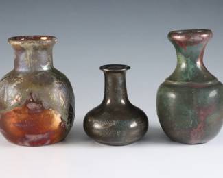Three early to mid 20th century miniature Pewabic Pottery vases attributed to Ira and Ella Peters. Bottle forms with iridescent glazes in shades of Dark Green, Oxblood and Gold. Taller Oxblood vase unmarked with numerals written in pencil at underside, taller Green vase incised "Ira / Ella" and shortest with smaller impressed circular "Pewabic Detroit" mark used c. 1925 and prior. Some surface wear and minor crazing. Up to 3 3/4" high. ESTIMATE $600-800