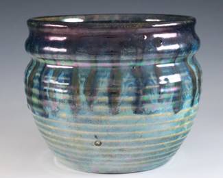 An early 20th century Pewabic Pottery vase. Bulbous form with linear ribbed body and iridescent drip glaze in shades Blue, Green and Brown. Smaller impressed circular "Pewabic Detroit" mark used c. 1925 and prior, also retains a partial medallion "Pewabic Detroit" paper label with two dots c. 1915-1930. Crazing, some burst air bubbles from production. 6" diameter x 4 7/8" high overall. ESTIMATE $800-1,200