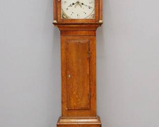 An early 19th century English Grandfather Clock by Robert Summerhayes. 8-day time and strike movement with painted iron dial with shell motifs, Arabic numerals, calendar aperture, marked "Robert Summerhayes, Ilminster". Oak case with Mahogany banding features a hood with broken arch crown and Brass finial over an arched door flanked by fluted columns with Brass capitols and bases, above a waist section with a long door on a molded bracket base. Older refinishing with some veneer loss, restored base, wear/losses to painted dial. 17 x 9 1/2 x 84 3/4" high overall. ESTIMATE $200-400