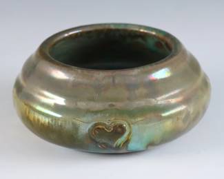 An early to mid 20th century miniature Pewabic Pottery bowl. Low stepped form with incised Heart decoration and iridescent glaze in shades of Green and Gold. Impressed circular "Pewabic PP Detroit" marks used c. 1930. Slight crazing, some scratches to underside. 3 1/2" diameter x 1 1/2" high overall. ESTIMATE $300-400
