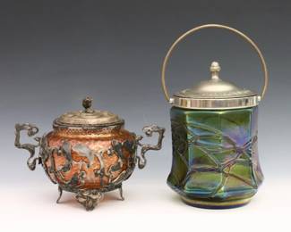Two turn of the century Bohemian Art Glass biscuit jars. Iridescent glass bodies in various colors with metal fittings and overlay. Minor surface wear and fleabites, metal with oxidation. Up to 7 1/2" high. ESTIMATE $200-300