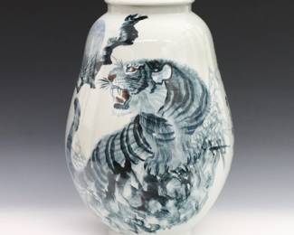 A Korean Blue and White porcelain vase. Tapered form with rolled rim and hand-painted decoration depicting a tiger among foliage. Calligraphy at one side of the body, three character mark at the underside. Crazing, light wear overall. 10 1/2" diameter, 14 1/2" high. ESTIMATE $600-800