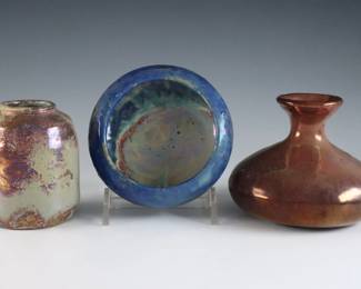 Three early 20th century miniature Pewabic Pottery vessels. Each with iridescent glazes, includes a cylindrical vase in Pale Green, Purple and Gold, a bottle form vase in Oxblood, Pale Green and Gold, and a bowl in Cobalt Blue, Pale Green and Gold. Cylindrical vase unmarked with "Pewabic" handwritten under the glaze, bottle vase with barely visible circular impressed mark, bowl with impressed circular "Pewabic Detroit" mark. Some crazing, very slight surface wear. Up to 3 3/4" diameter and 3" high. ESTIMATE $1,000-1,500
