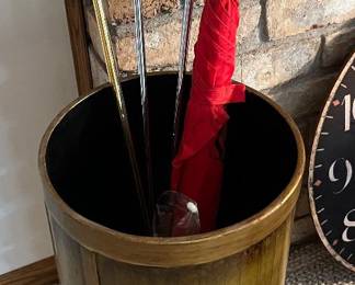 Umbrella stand containing a selection of putters (Callaway, Affinity, etc.) and umbrellas.