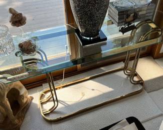 Console table with brass base and clear glass top.