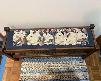 Wooden bench features a tapestry seat depicting rabbits and tulips.