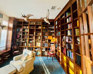 bibliophile's dream come true, this expansive home library features floor-to-ceiling custom-built wooden bookshelves that wrap the room, filled with significant personal collection