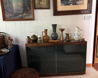 Vintage pottery. Round, leather ottoman. Bookcase with sliding glass doors