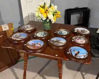 Framed collectors plates on top of drop leaf table.