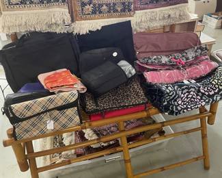 Bamboo bench holding misc bags and rugs