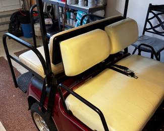Yamaha Gas Golf Cart finished in a rich metallic burgundy with cream upholstery. This well-maintained cart features comfortable 4-passenger seating, a fold-down rear seat with cargo deck, custom alloy wheels, full windshield, sun top, woodgrain-style dashboard with multiple cup holders, seat belts, and headlights. A dependable gas-powered cart that’s perfect for cruising The Villages or around the neighborhood.
