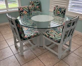 Beautiful 8-piece coastal dining set featuring a beveled glass tabletop, sculptural white rattan pedestal base, and six matching rattan dining chairs with vibrant tropical cushions. A stunning centerpiece for a breakfast nook, dining room, sunroom, or Florida home.