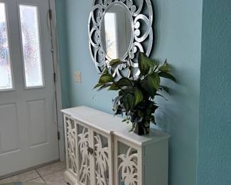 Beautiful coastal accent cabinet featuring decorative palm tree mirrored doors, an elegant white finish, and interior storage. Perfect for a foyer, dining room, living room, or Florida room with coastal, tropical, or beach-inspired décor.