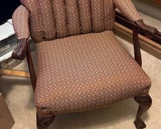 Vintage Upholstered Claw Foot Chair — This vintage wingback chair features a classic shell-back design with plush upholstered fabric in a muted red geometric pattern. The frame is crafted from carved dark wood with detailed claw feet and scrolled armrests, showcasing quality craftsmanship. The chair measures approximately 38 in height, 29 in width, and 28 in depth, making it suitable for a traditional living or bedroom seating area. It is in good condition with some minor wear consistent with age, adding to its vintage appeal. A timeless piece ideal for collectors or those seeking classic accent seating.