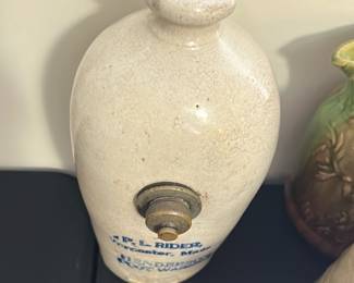 P.L. Rider Hendersons Foot Warmer — This vintage P.L. Rider foot warmer from Worcester, Massachusetts, showcases classic stoneware craftsmanship with a crackled cream glaze. Featuring a functional brass knob on its front, this Hendersons model is a practical and collectible piece of Americana. The item stands approximately 9 inches tall and 5 inches wide, making it suitable for personal use during cold weather. It shows typical age wear and surface crackling, consistent with its vintage origin, but remains structurally sound. A wonderful addition for collectors of antique home warming devices and stoneware.