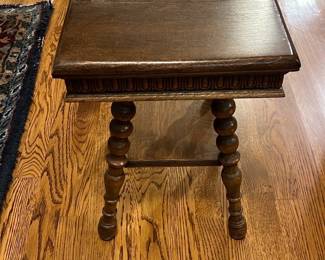 Carved Oak Turned Leg Side Table — This charming small side table features rich oak wood construction with elegantly turned legs and detailed carved apron accents. The dark stained finish highlights the wood grain and adds a warm, classic touch suitable for various interior settings. Measuring approximately 18 inches in height, 18 inches wide, and 14 inches deep, it fits perfectly as an accent or occasional table in a living room. The table is in good condition with minor surface wear consistent with age but remains sturdy and functional. A versatile vintage piece, it complements both traditional and eclectic decor styles.